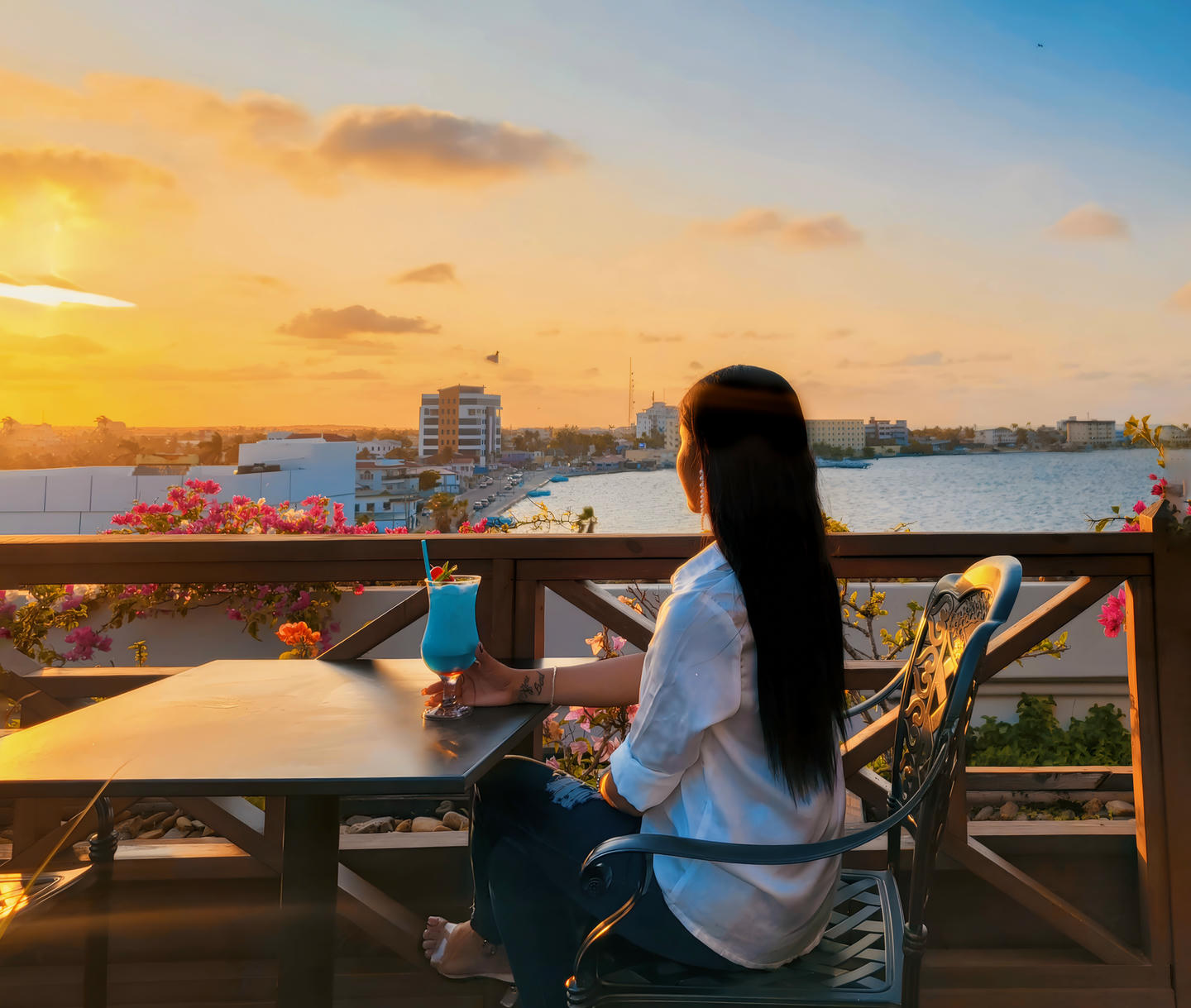 Mujer cenando en el restaurante Vino Tino en la azotea, Belice, mirando hacia el atardecer.