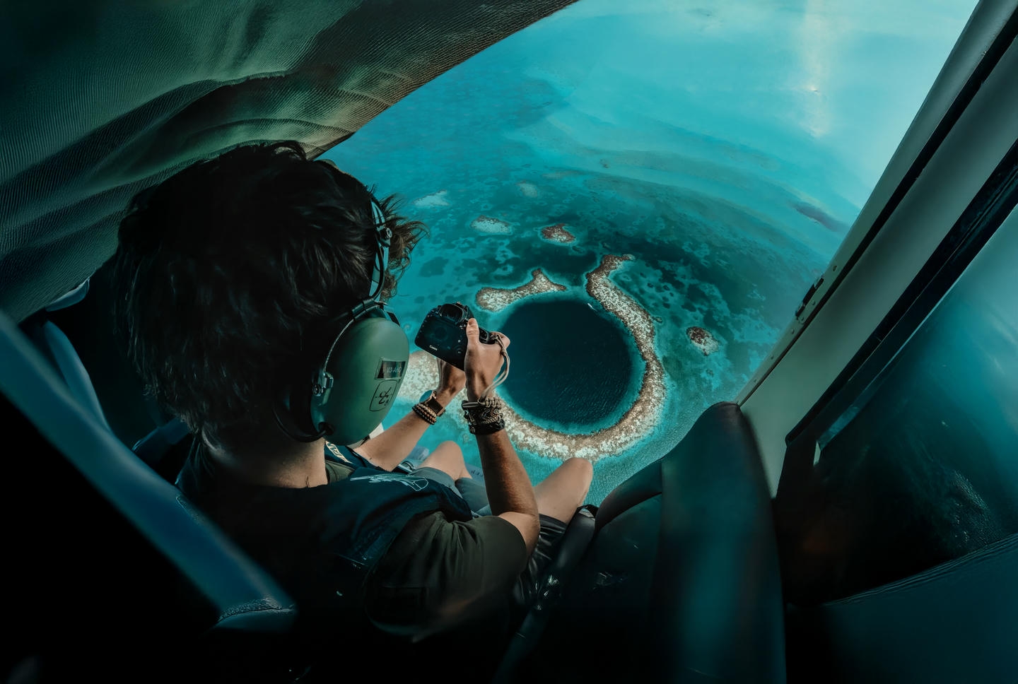Man taking photo of the Great Blue Hole from inside a helicopter with a digital camera. Man taking photo of the Great Blue Hole from inside a helicopter with a digital camera.